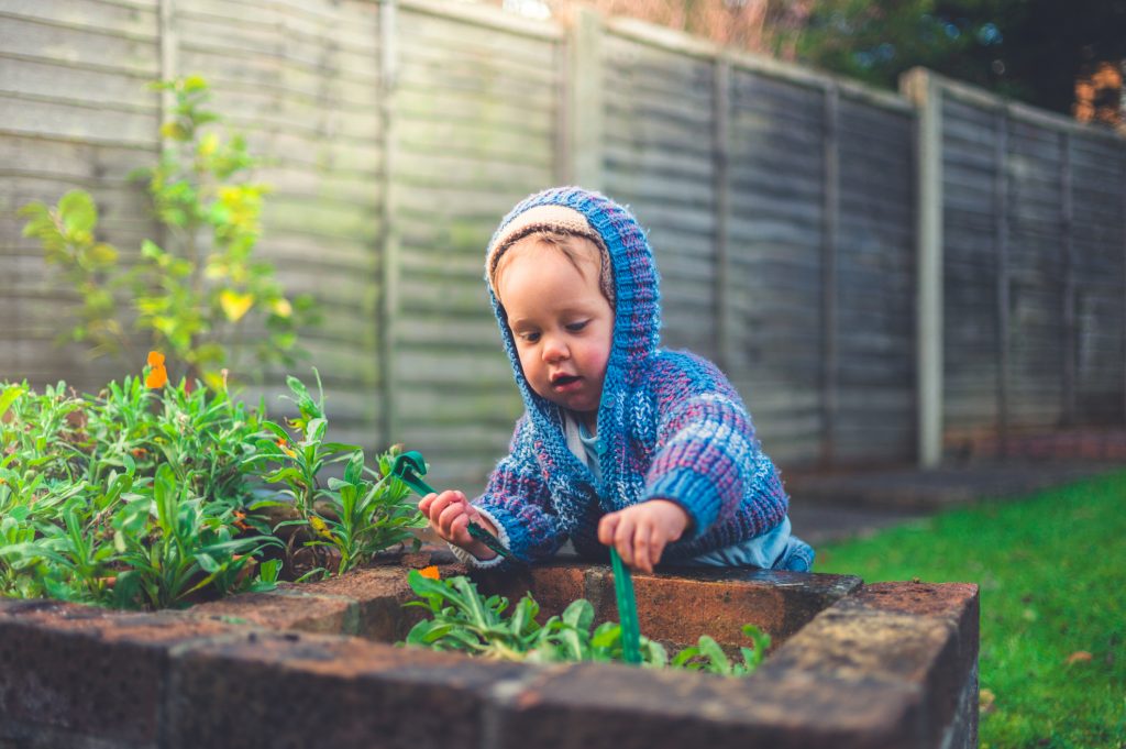 A cute little baby is doing some gardening outside in winter