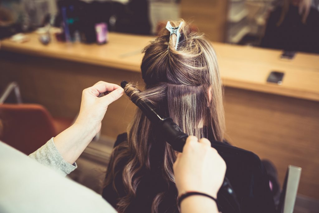 woman getting her hair curled by hairdresser